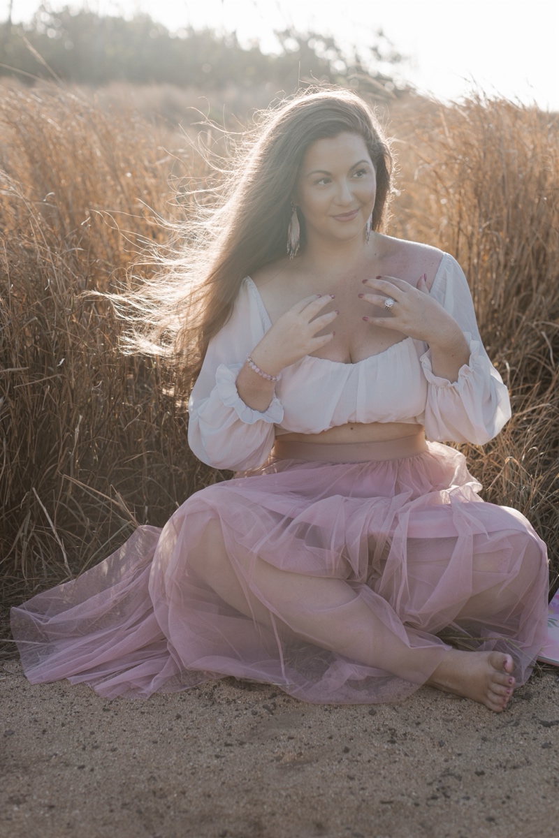 Amy McNally seated outdoors in a pink skirt